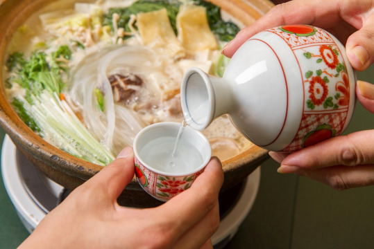 鍋料理と一緒に温かい燗酒を楽しむ様子